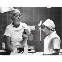 Black and white photo of Virginia Apgar, MD, evaluating a newborn.
