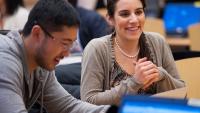 Two students sitting in a lecture hall.