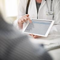 Doctor's hand points to screen of tablet.